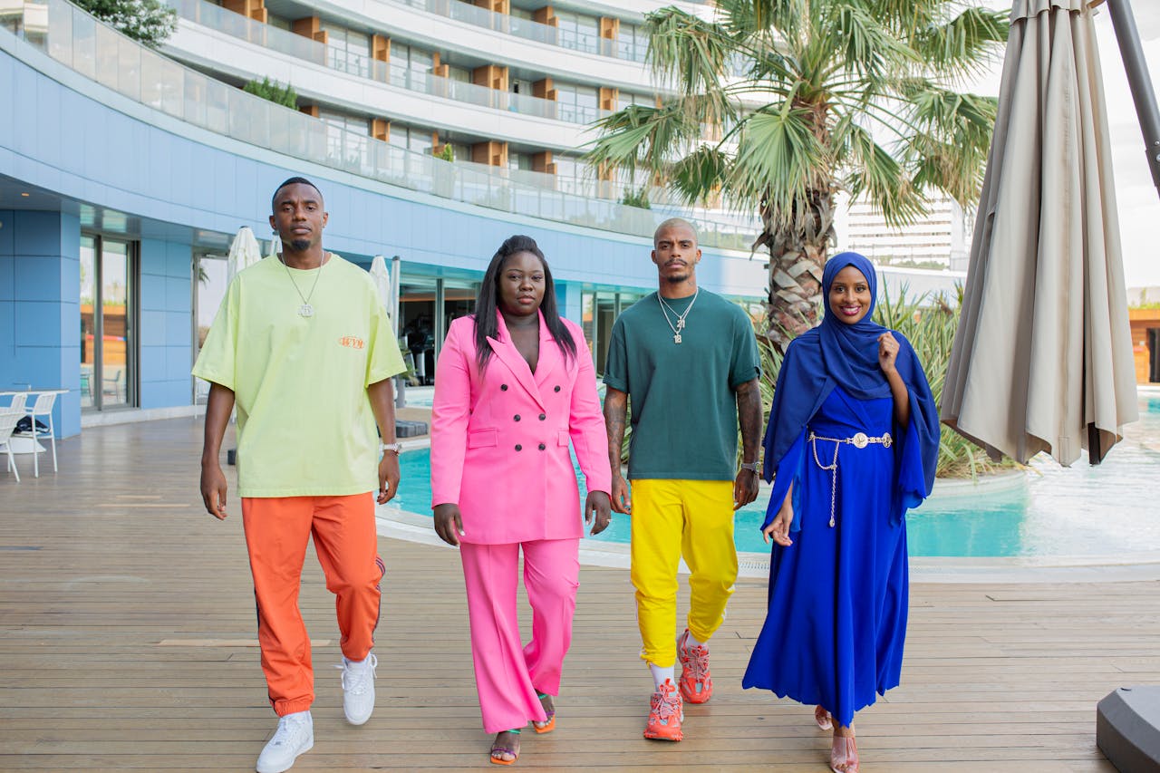 Stylish diverse group in colorful outfits walking by a modern hotel pool.